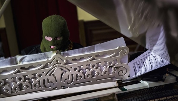 A masked man plays the grand piano to an audience of anti-government protesters in the Kiev City Hall